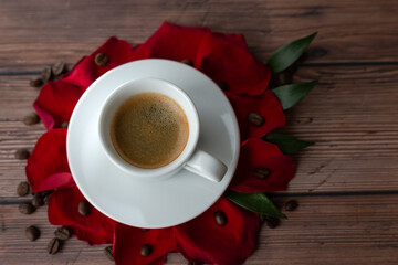 Roses petals on wooden background with cup of coffee and copy space.