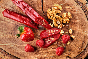 slicing Churchkhela, strawberries and nuts on a wooden background, top view, serving