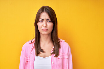 Fototapeta premium Young brunette woman with offended upset face isolated in yellow studio