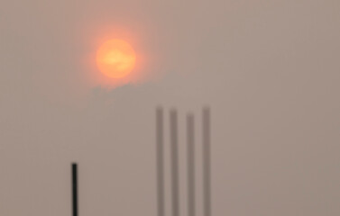 The red sun at dawn was fog over the tip of the rebar in the construction site.