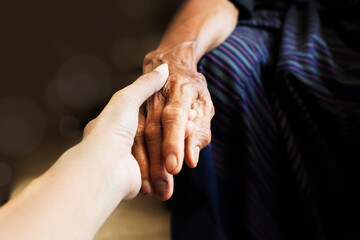 Helping hand for the elderly concept with young hand holding old, wrinkled hand with copy space -...