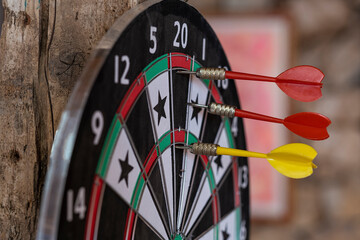 Photo of a dart board with three darts arrows. Dart arrows hit on bull eyes of dartboard. The...