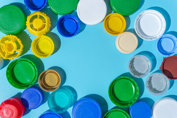 Colorful plastic bottle caps on a blue background, collecting plastic for recycling and reuse. copy space