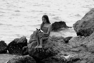 person is sitting on the rocks and reading a book