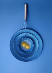 Baking Whisk Wtih Egg York on Creative Blue Background  