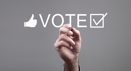 Male hand holding a pen write vote on elections in screen.