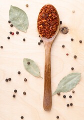 Ground chili in wooden spoon on wooden background