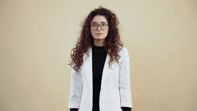 The motionless young woman with curly hair, has a tic in her eyes, blinks insistently. Young hipster in gray jacket and white shirt,