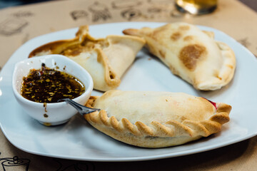 Argentinean pie with spicy sauce on white plate