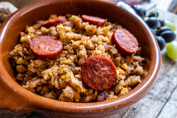 Migas Manchegas with chorizo in a clay pot, served with grapes, garlic and bread. It is a Spanish dish, traditional from Castilla la Mancha.
