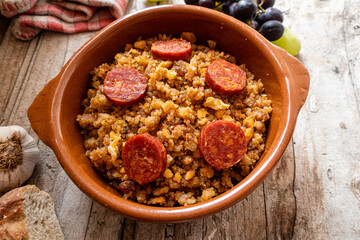Migas Manchegas with chorizo in a clay pot, served with grapes, garlic and bread. It is a Spanish dish, traditional from Castilla la Mancha.