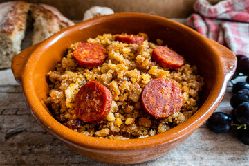 Migas Manchegas with chorizo in a clay pot, served with grapes, garlic and bread. It is a Spanish dish, traditional from Castilla la Mancha.