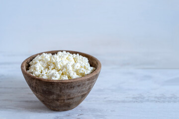 Cottage cheese in wooden bowl over white background with copy space.