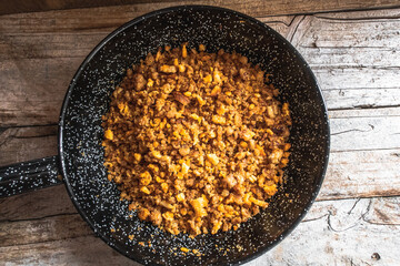 Migas Manchegas, a traditional dish from Castilla la Mancha in Spain, on a rustic wooden background. 