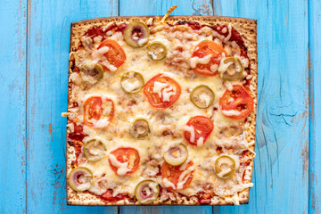 Matzah Pizza on blue wooden background. Food ideas for Passover.
