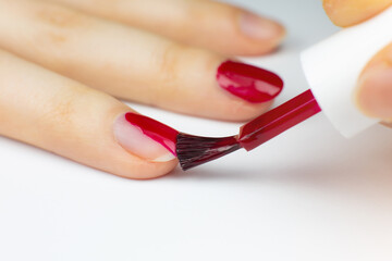 Woman applies red nail polish..Girl making a manicure. Salon procedures at home. Beautiful hands and nails. Close up, macro photo.