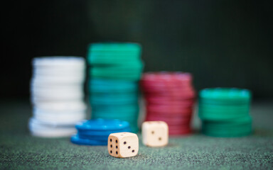 Casino poker chips stack dice on green felt background.