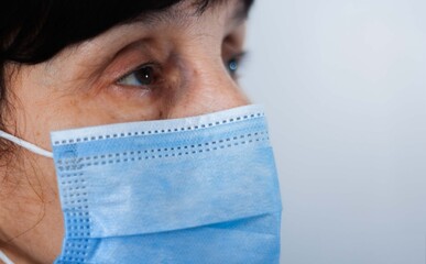 Coronavirus quarantine and Air pollution pm2.5 concept. Face of old sick woman wearing blue respirator mask for protect. Wuhan, China epidemic virus symptoms background.