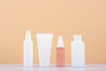 Skin care products in a row on white table against beige background. Beauty and cosmetic concept