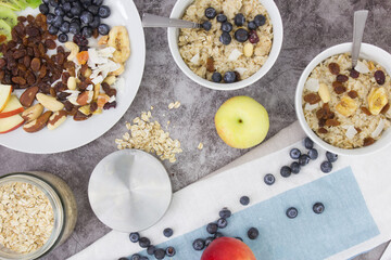Cooking breakfast. Cooked oatmeal and a plate with dried fruits, nuts, fruits and berries on a gray background.