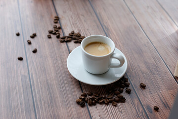 Cup of hot coffee on wooden table, surrounded by coffee beans