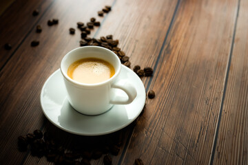 Cup of hot coffee on wooden table, surrounded by coffee beans