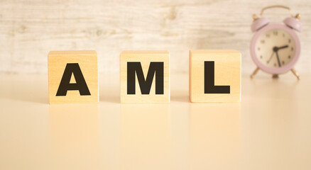 The word AML consists of wooden cubes with letters, top view on a light background.