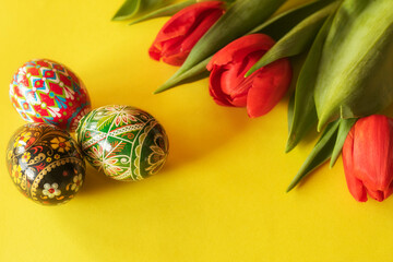 Three colorful Easter eggs with red tulips 
