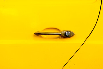 metal door handle of a yellow vintage car