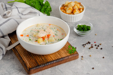 Salmon soup with cream, potatoes, carrots, herb and croutons in a bowl on a gray concrete background. Copy space.