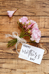 Happy Mother's Day card and pink flowers on a wooden table