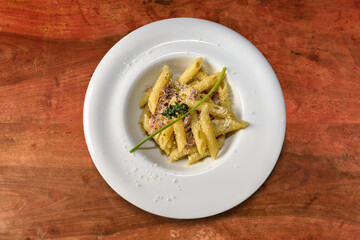 penne pasta with sausage meat sauce and thyme. macaroni Italian Pasta in white dish on wooden table, top view, flat lay