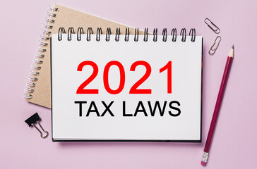 Text 2021 tax laws on a white notepad with office stationery background. Flat lay on business, finance and development concept