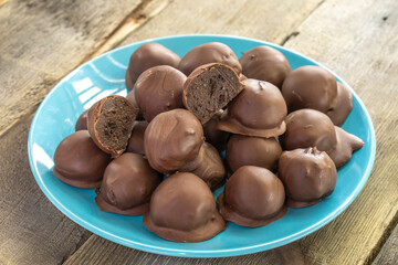 Chocolate Truffles on blue plate isolated on wooden background. food concept