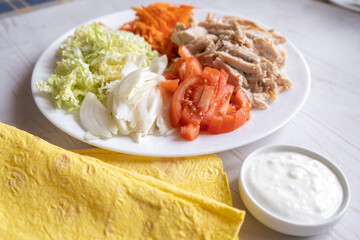 Shaurma, burrito, chicken roll or pita with chicken, fresh vegetables, cream sauce and corn flour lavash