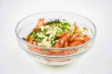 fresh salad with cabbage, tomatoes and greens in a glass bowl