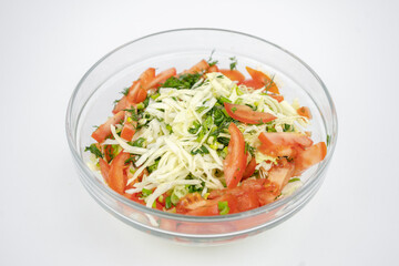 fresh salad with cabbage, tomatoes and greens in a glass bowl