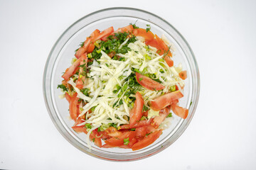 fresh salad with cabbage, tomatoes and greens in a glass bowl