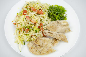 diet dish on a plate with fresh salad with cabbage, tomatoes, greens and chicken breast