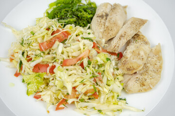 diet dish on a plate with fresh salad with cabbage, tomatoes, greens and chicken breast