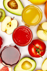 juices in glass glasses on a background of fruits on a white background