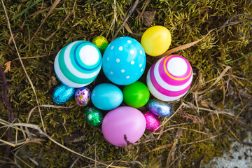 Fototapeta na wymiar Top view of several painted eggs and chocolates on the grass. Colorful easter eggs in the garden.