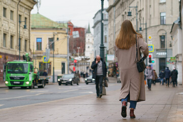 Moscow city street during coronavirus pandemic. People wear, use, put on protective face mask. Photography of back of young woman hurrying up. Lifestyle concept