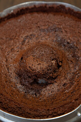 Chocolate cake in the form, withered, sank. Wooden background, view from above. Space for design.