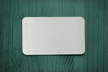 White business card template on a green wooden background.