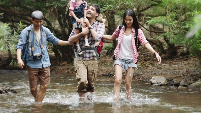 A group of young Asians are planning and looking at maps for camping in the forest.Asian and caucasian are backpackers.Tourism, adventure and summer vacation concept