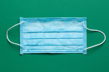 Surgical masks with rubber ear straps on a green background. Typical 3-ply surgical mask to cover the mouth and nose. Procedure mask from bacteria.