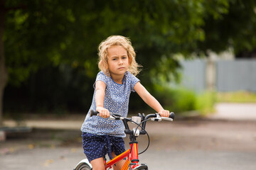 Fototapeta na wymiar The little girl rides a bike in the city