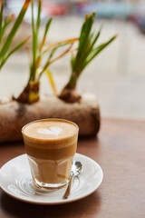 Cup of coffee on the table in the cafe near window. Cappuccino or latte in glass
