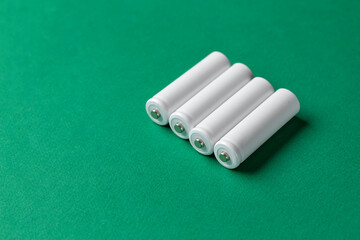 Rechargeable AAA batteries in white on a green background. Place for text.